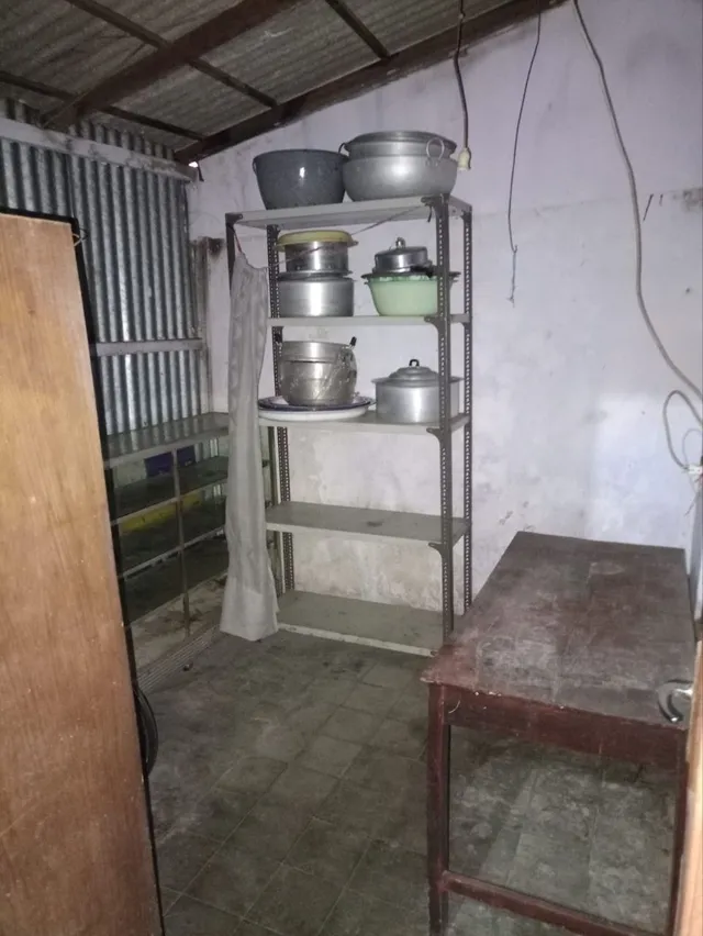 Sesudah: lantai gudang kosong dan lega, panci dan perabot masak tertata di rak besi, meja kayu di sisi kanan