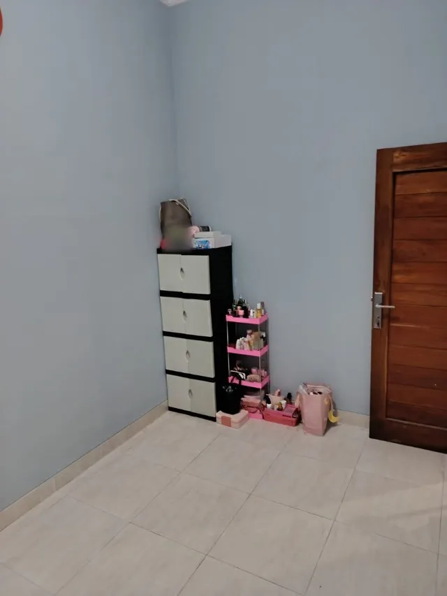 Sesudah: lantai kamar kosong dan bersih, barang tersimpan di lemari laci dan rak kecil di sudut kamar