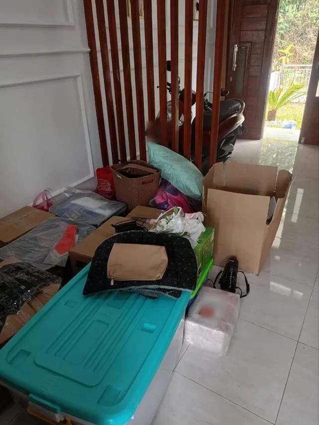 Sebelum: ruang depan penuh kardus, kontainer plastik, tas, dan barang pindahan di lantai